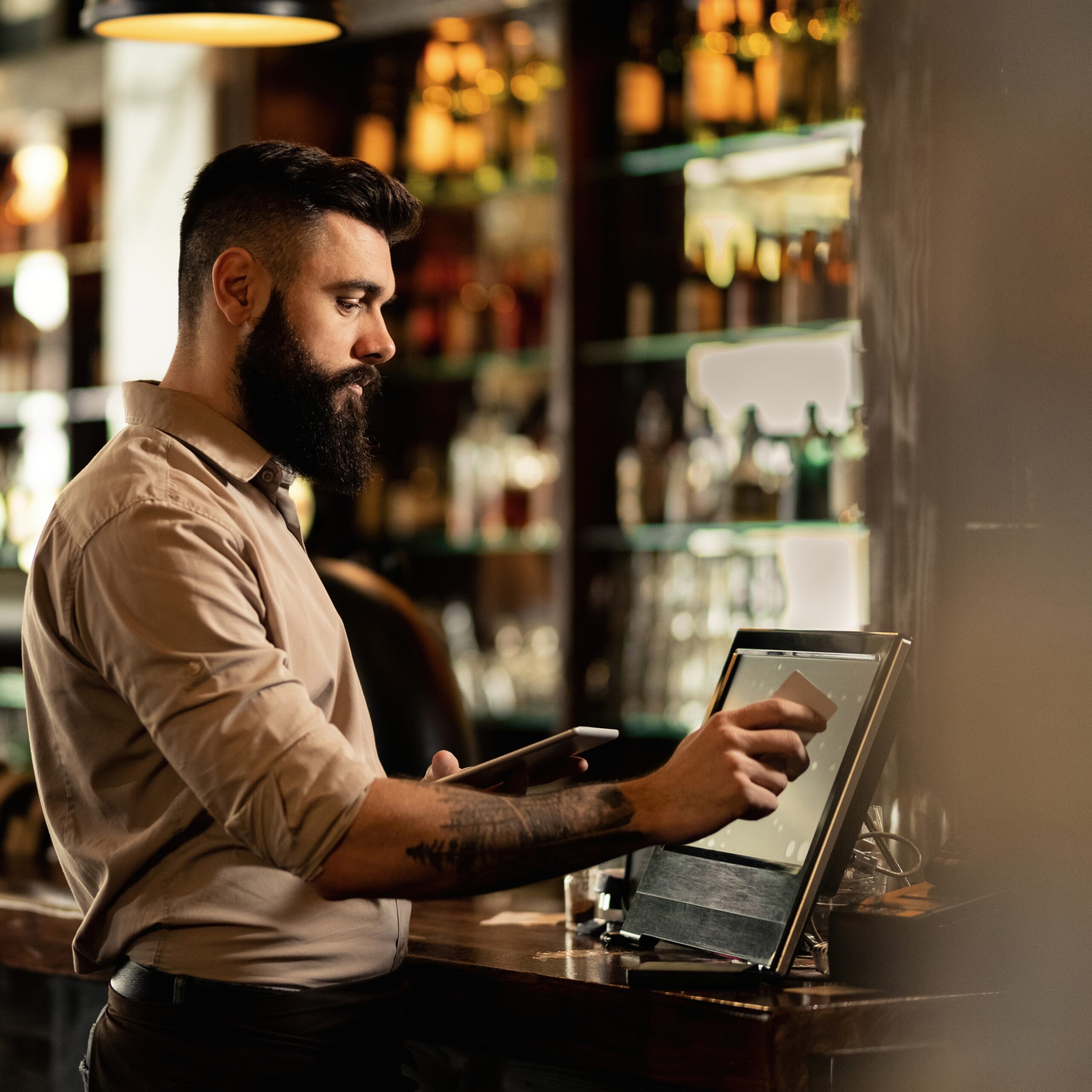 Young barista working at cash register in a bar.